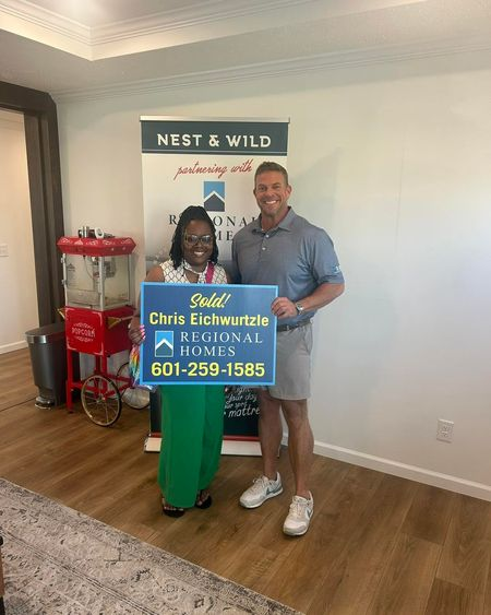 Two people celebrating a home sale with a Regional Homes sold sign