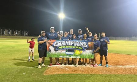 A team celebrating with a champions banner on a ball field